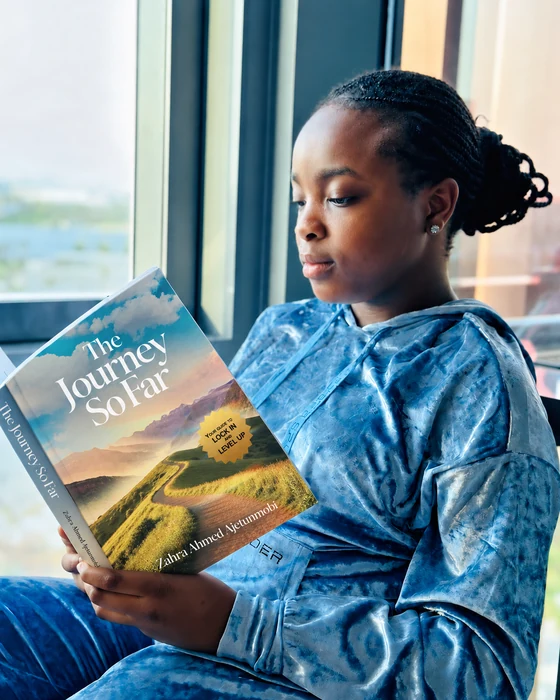 A young reader enjoying The Journey So Far beside a window